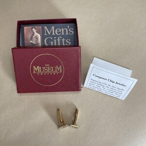 May include: A pair of gold-toned cufflinks featuring computer chip inserts, presented in a burgundy box with The Museum Company logo. Included is a card titled Men's Gifts and an informational insert titled Computer Chip Jewelry with text.
