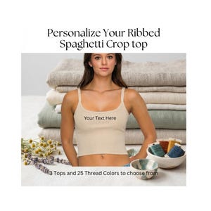 May include: A beige ribbed spaghetti strap crop top with the text Your Text Here printed on the front. The image includes the text Personalize Your Ribbed Spaghetti Crop top and 3 Tops and 25 Thread Colors to choose from.
