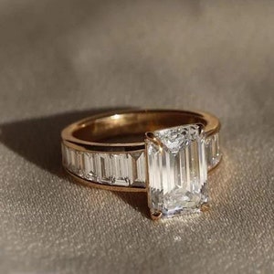 May include: A gold ring featuring a large emerald-cut diamond centre stone and smaller baguette diamonds set in the band.