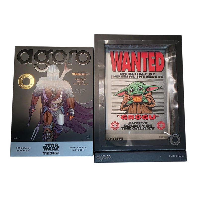 May include: Two Star Wars collectibles. One box features The Mandalorian, the other a Grogu "Wanted" poster. Both are in black frames. The box reads "Pure Silver, Pure Gold" and "Engraved Foil Blind Box."