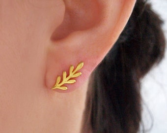 May include: A pair of gold leaf earrings. The earrings are small and delicate, and they feature a simple leaf design.