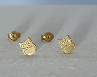 May include: A pair of gold-toned owl stud earrings. The owls are detailed with small eyes and a rounded body.