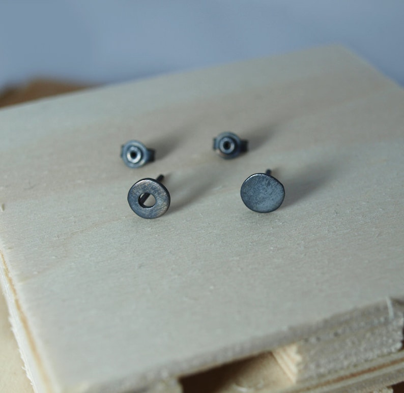 May include: Three silver stud earrings, two with a round shape and one with a circle design.