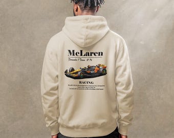 Puede incluir: Una sudadera con capucha beige con un logotipo negro de McLaren Formula 1 Team y un gráfico de un coche de carreras. El texto "Racing" está impreso debajo del coche.