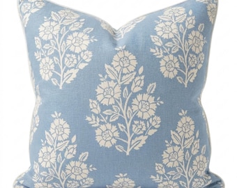 May include: A square throw pillow featuring a light blue fabric base with a repeating white floral pattern. The design consists of stylized flower sprigs arranged in a symmetrical layout. The pillow is finished with white piping along the edges.