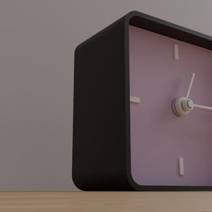 May include: A square black alarm clock with a light purple face. The clock has white hands and white rectangular markers for the hours. The clock is sitting on a wooden surface.