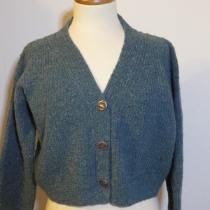May include: A teal blue knitted cardigan with a v-neck and gold buttons.
