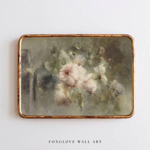 May include: A framed floral print featuring soft pink roses and white flowers against a muted green background. The artwork is enclosed in a gold-colored frame. The text "FOXGLOVE WALL ART" is printed at the bottom of the image.