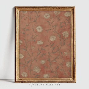 May include: A framed wall art print featuring a floral pattern. The artwork has a salmon-colored background with a repeating design of white flowers and green stems. The frame is a gold color, and the text "FOXGLOVE WALL ART" is at the bottom.
