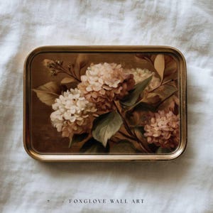 May include: A rectangular decorative tray with a floral painting. The artwork features white and peach-colored hydrangea blooms with green leaves against a brown background. The tray has a gold-colored frame. The text "FOXGLOVE WALL ART" is at the bottom.