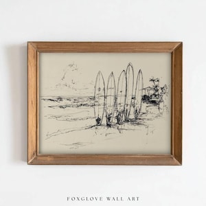May include: A framed black and white sketch of surfboards on a beach. The artwork features five surfboards standing upright in the sand near the ocean. The frame is made of wood, and the text "FOXGLOVE WALL ART" is at the bottom.