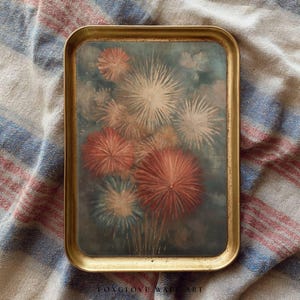 Könnte beinhalten: Ein rechteckiges Serviertablett mit goldfarbenem Rahmen. Die Oberfläche des Tabletts zeigt ein Gemälde von Feuerwerk in Rot-, Weiß- und Orangetönen vor einem teal-farbenen Hintergrund. Der Text "LONGGLOVE WALL ART" befindet sich unten.