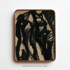 May include: Abstract black ink painting on a beige background, framed in a gold-toned rectangular frame. The artwork features bold brushstrokes and the text "FOXGLOVE WALL ART" at the bottom.