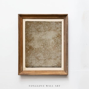 May include: A framed piece of wall art with a textured, speckled design in shades of beige and brown. The artwork is encased in a rectangular, wooden frame. The text "FOXGLOVE WALL ART" is at the bottom of the image.