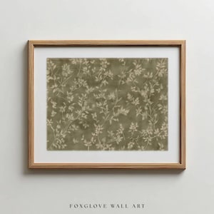 Könnte beinhalten: Ein gerahmter Druck mit einem botanischen Muster aus zarten, hellfarbigen Blättern und Ranken vor einem gedämpften olivgrünen Hintergrund. Das Kunstwerk ist in einem Holzrahmen und einem weißen Passepartout eingefasst. Der Text "FOXGLOVE WALL ART" steht unten.