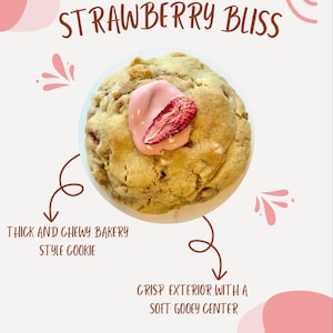 May include: A close-up of a large, thick, and chewy bakery-style cookie with a crispy exterior and a soft, gooey center. The cookie is topped with a pink chocolate swirl and a dried strawberry. The cookie is labeled "Strawberry Bliss".