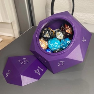 May include: A purple, multi-sided dice box with a lid, filled with various coloured polyhedral dice. The box is open, revealing the dice inside. The numbers are etched in silver.