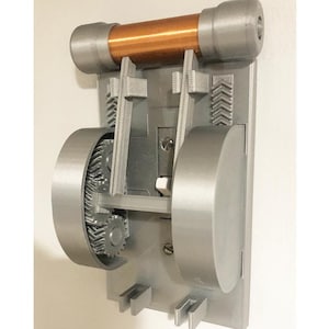 May include: A gray and copper-colored mechanical device with gears, a cylindrical copper tube, and a rectangular base. The device is mounted on a white surface and features intricate internal components.