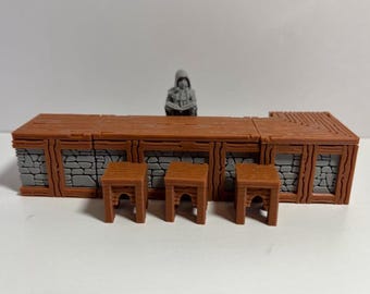 Pode incluir: Um bar de madeira castanha em miniatura com três bancos a condizer. O bar tem uma fachada de pedra e um tampo de madeira. Uma pequena figura de uma pessoa com um capuz está atrás do bar.