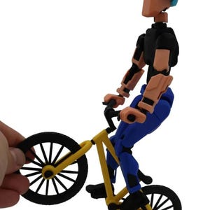 May include: A yellow and black BMX bike with a blue and black articulated action figure riding it. The figure is wearing a blue helmet.