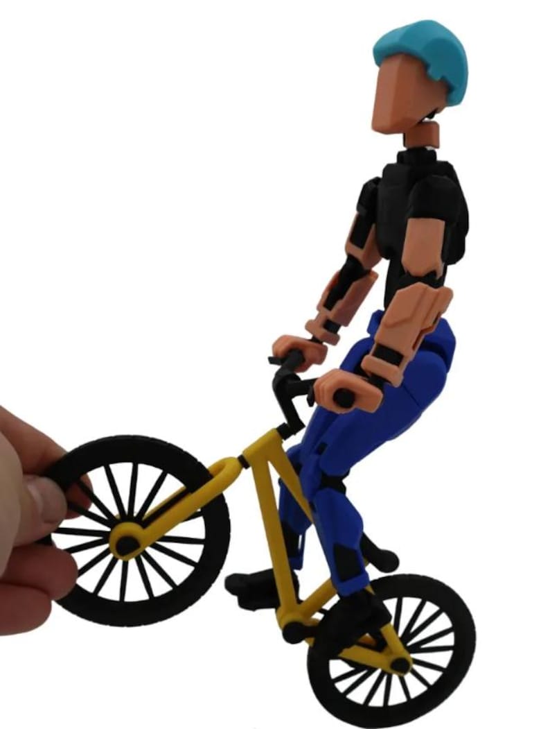 May include: A yellow and black BMX bike with a blue and black articulated action figure riding it. The figure is wearing a blue helmet.