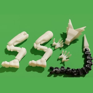 Può includere: Una collezione di parti di modello articolate stampate in 3D, tra cui gambe, mani, una testa e una coda segmentata. Le gambe e le mani sono bianco sporco, la testa è bianca e la coda è nera, su sfondo verde.