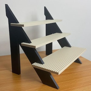 May include: A black wooden shelf unit with three tiers. The shelves are made of a light beige material with a ribbed texture.