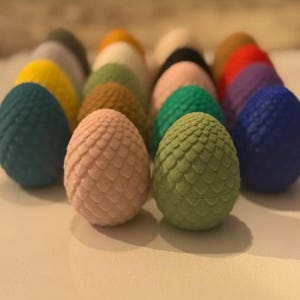 May include: A collection of colorful dragon eggs, each with a unique textured surface. The eggs are arranged in a semi-circle, with the green egg in the center.