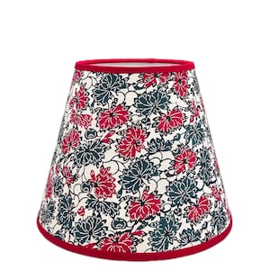 May include: A red and white lampshade with a floral pattern. The lampshade is cone-shaped and has a red trim.