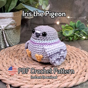 May include: A gray crocheted pigeon toy with black plastic eyes, a small dark beak, and orange feet. The pigeon features a light purple band around its neck and mottled gray wing patterns. Text reads Iris the Pigeon and PDF Crochet Pattern.