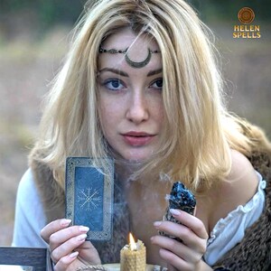 Puede incluir: Una mujer rubia con una diadema de media luna, sosteniendo una carta de tarot con un dise&ntilde;o de copo de nieve y un cristal azul. Tambi&eacute;n se ven una vela encendida y el texto "HELEN SPELLS".