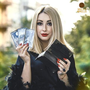 Puede incluir: Una mujer rubia con labios rojos sostiene cartas del tarot y un libro oscuro. Las cartas tienen ilustraciones detalladas. El libro es negro con detalles dorados. La imagen tiene un fondo borroso con el texto "HELEN SPELLS".