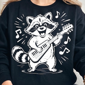 May include: Black sweatshirt featuring a white illustration of a raccoon playing a guitar-like instrument. The raccoon has a happy expression and is surrounded by musical notes. The design has a distressed, vintage look.