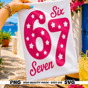 Może przedstawiać: Biała tkanina z różowymi słowami "Six 67 Seven". Cyfry wypełnione są białymi gwiazdami. Tkanina trzymana jest w dłoni z złotą bransoletką i niebieskim lakierem do paznokci.