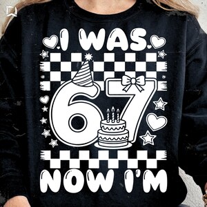 Peut inclure: Sweat-shirt noir avec un motif blanc indiquant "I WAS. 67. NOW I'M." Le chiffre 67 est orné d'un chapeau de fête, d'un nœud et d'un petit gâteau avec trois bougies. Des cœurs et des étoiles entourent le texte et les chiffres.