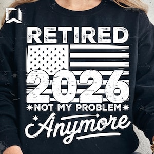 Peut inclure: Sweat-shirt noir avec un motif blanc indiquant "RETIRED 2026 NOT MY PROBLEM Anymore" et un drapeau américain. Le design est vieilli pour un effet vintage.