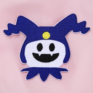 Könnte beinhalten: Gestickter Aufnäher mit einer Cartoonfigur mit blauem Hut und Gesicht, weißem Gesicht, schwarzem Mund und Augen sowie einem gelben Punkt auf dem Hut. Auf rosa Hintergrund.