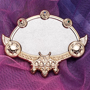 以下が含まれることがあります： 銀色の中心部を持つ、豪華な金色の装飾フレーム。フレームには、赤、青、緑の宝石が付いた小さな円形のアクセントや、翼のようなデザインなど、詳細な装飾が施されています。フレームは紫とピンクの背景に配置されています。