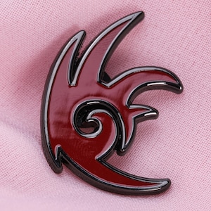 Könnte beinhalten: Ein rot-schwarzer Emaille-Pin mit einem stilisierten Flammen-Design. Der Pin hat eine glänzende rote Mitte mit schwarzem Umriss, was einen auffälligen Kontrast erzeugt. Das Design umfasst geschwungene Linien und ein wirbelndes Element, das ein dynamisches Thema suggeriert.