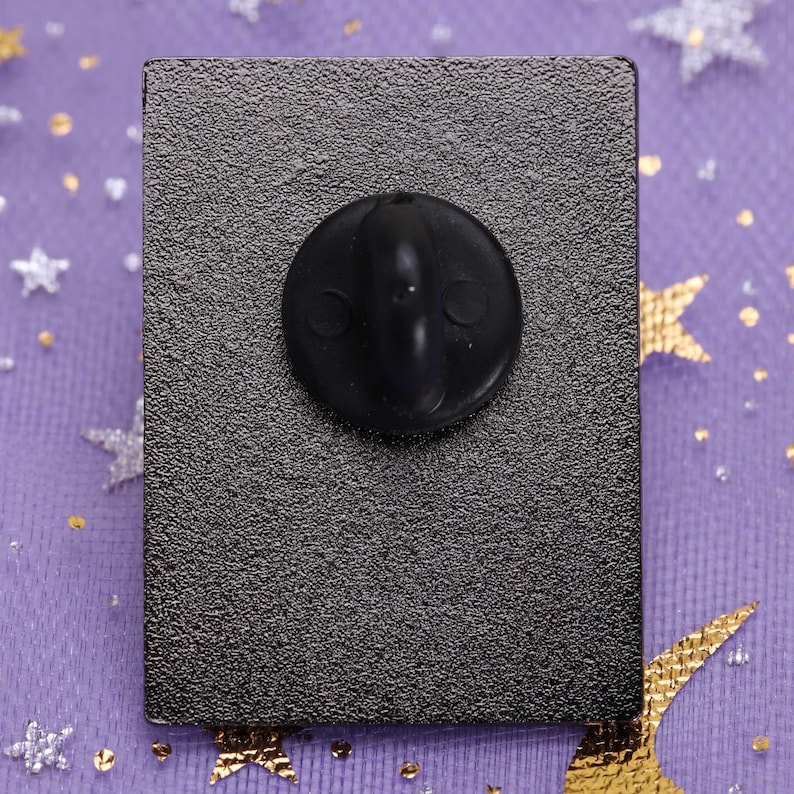 May include: The back of a black enamel pin with a black rubber clutch back.