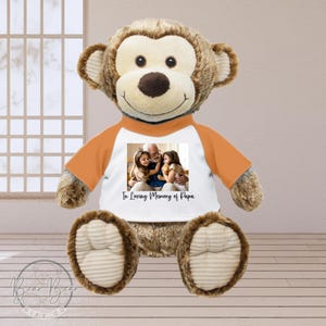 May include: A brown plush monkey wearing an orange and white shirt with a photo of a family and the text "In Loving Memory of Papa".