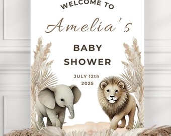 May include: A white welcome sign with brown text that reads "Welcome to Amelia's Baby Shower July 12th 2025". The sign is decorated with illustrations of a brown lion and a white elephant, surrounded by beige pampas grass.
