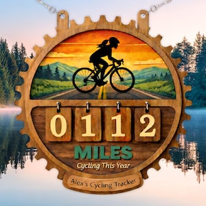 May include: Wooden cycling tracker with a gear-shaped frame. The center features a cyclist silhouette on a road with a scenic background. The tracker displays "0112 MILES Cycling This Year" and "Alex's Cycling Tracker".