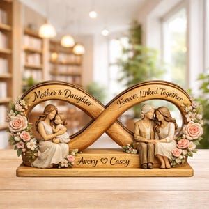 May include: A wooden infinity sculpture with the words "Mother & Daughter" and "Forever Linked Together." The sculpture features two sets of figures: a mother and child, and a mother and daughter. Pink roses and floral accents adorn the sides.