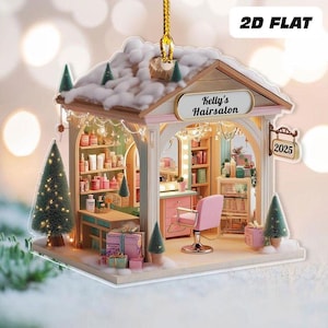 May include: A miniature Christmas ornament shaped like a hair salon, featuring a pink and white facade. The ornament has a sign that reads "Kelly's Hair Salon" and "2025". The interior is decorated with miniature beauty products and a pink salon chair.