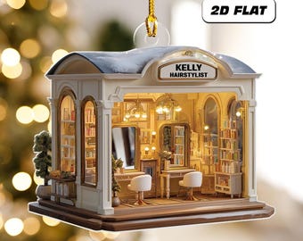 May include: A 2D flat ornament shaped like a miniature hair salon. The ornament features a white exterior with a blue roof and the text "KELLY HAIRSTYLIST". Inside, there are mirrors, chairs, and shelves filled with products. The ornament is suspended by a gold string.