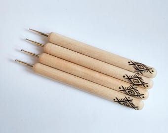 Op de afbeelding: Set van vier houten gereedschappen met metalen punten voor knutselen en nagelkunst. Elk gereedschap heeft een geometrisch ontwerp dat in het hout is gebrand.