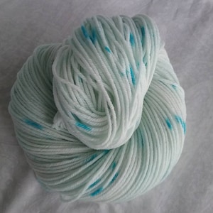 May include: A skein of white yarn with blue speckles. The yarn is soft and fluffy, and it would be perfect for knitting or crocheting.