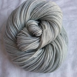 May include: A skein of light gray yarn with a subtle blue ombre effect. The yarn is made of a soft, natural fiber and is perfect for knitting or crocheting.