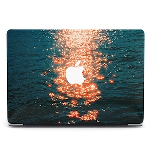 Puede incluir: Funda para portátil con una serena escena acuática con reflejos de sol brillantes. El diseño presenta un fondo verde azulado oscuro con reflejos naranja y amarillo brillante, y un logotipo de Apple blanco.